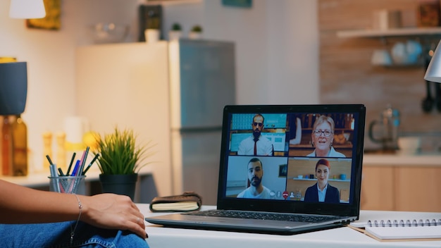 Business woman having webinar studying from home using internet technology on laptop in midnight. Lady using notebook with network wireless talking on virtual meeting at night doing overtime