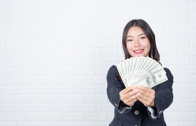 Free photo business woman holding banknote, cash separately, white brick wall made gestures with sign language.