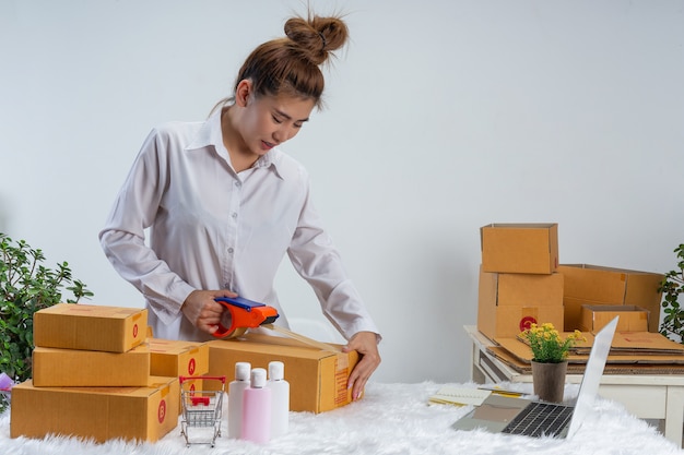 A business woman is working online and traing to reply customer  at home office packaging on wall.