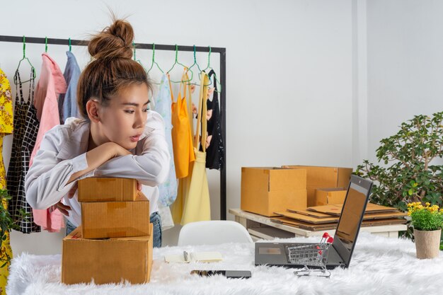 A business woman is working online and traing to reply customer  at home office packaging on wall.