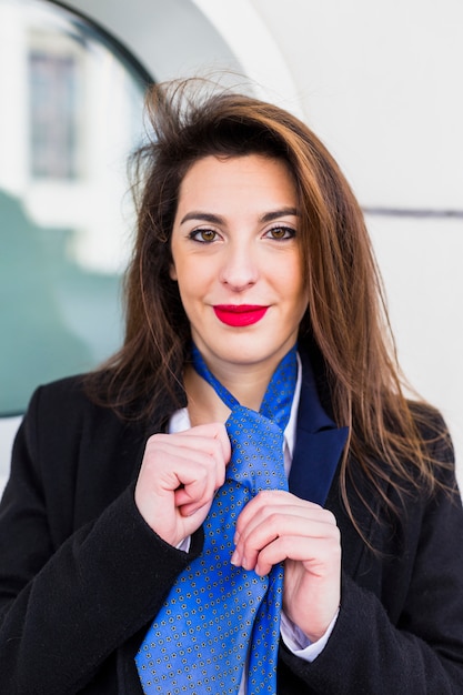 Business woman knotting blue tie 