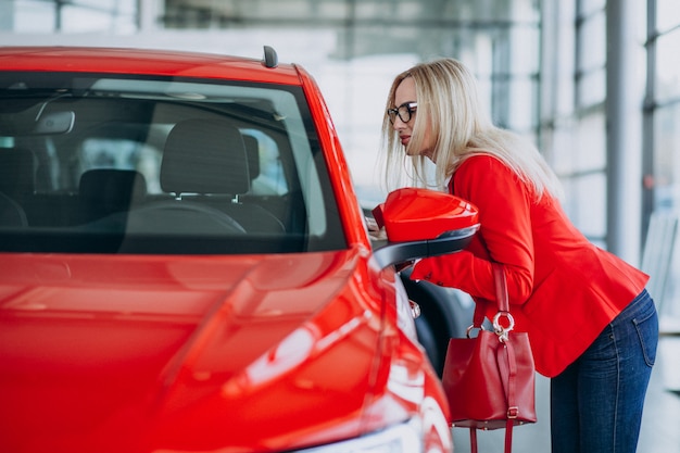 Donna di affari che cerca un cellulare automatico ad una sala d'esposizione dell'automobile