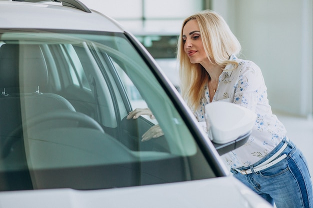 Donna di affari che cerca un cellulare automatico ad una sala d'esposizione dell'automobile