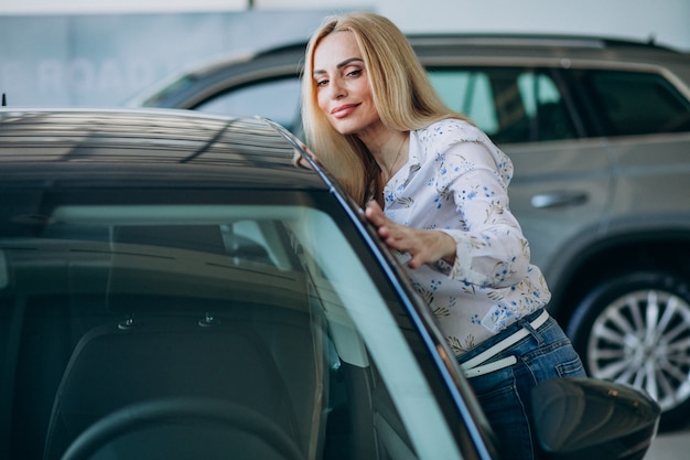 Donna di affari che cerca un cellulare automatico ad una sala d'esposizione dell'automobile