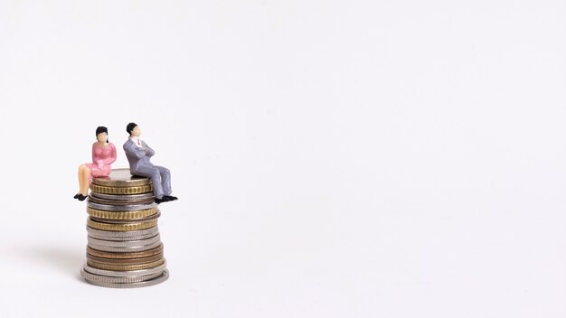 Business woman and man sitting on a pile of coins copy space