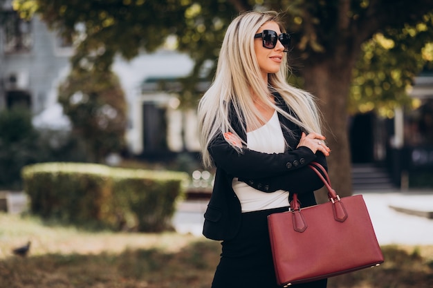 Foto gratuita donna d'affari nel parco con borsa rossa