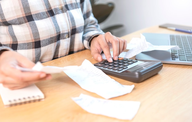 Business woman pressing the calculator calculate the various costs that must be paid by the bill invoices held and placed on the table.