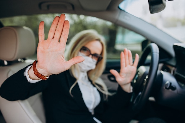 Деловая женщина в защитной маске сидит внутри автомобиля с помощью антисептика