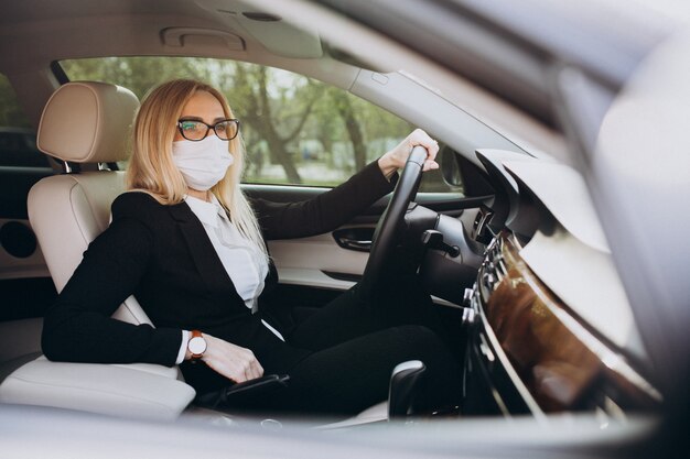 Business woman in protection mask sitting inside a car