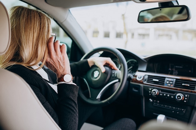 Business woman in protection mask sitting inside a car