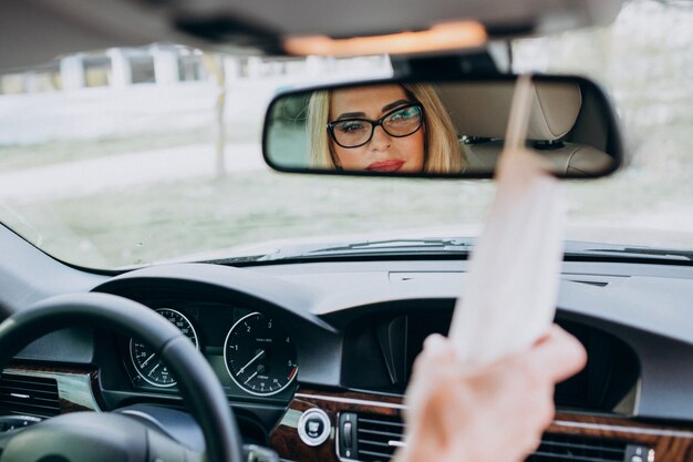 Business woman in protection mask sitting inside a car