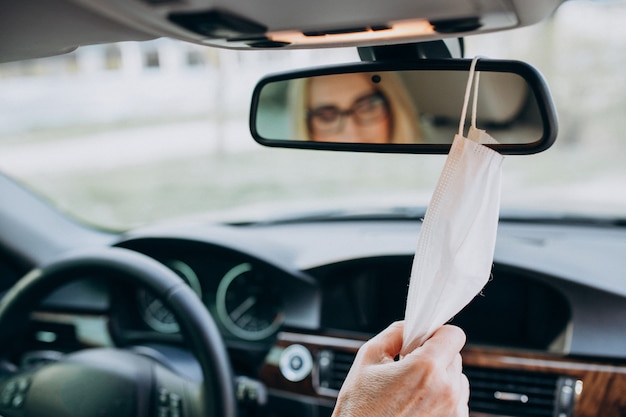 Business woman in protection mask sitting inside a car