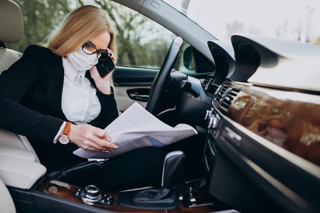 Business woman in protection mask sitting inside a car