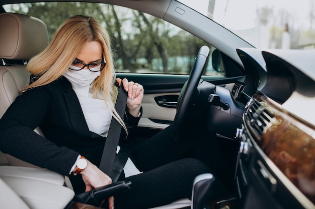 Business woman in protection mask sitting inside a car