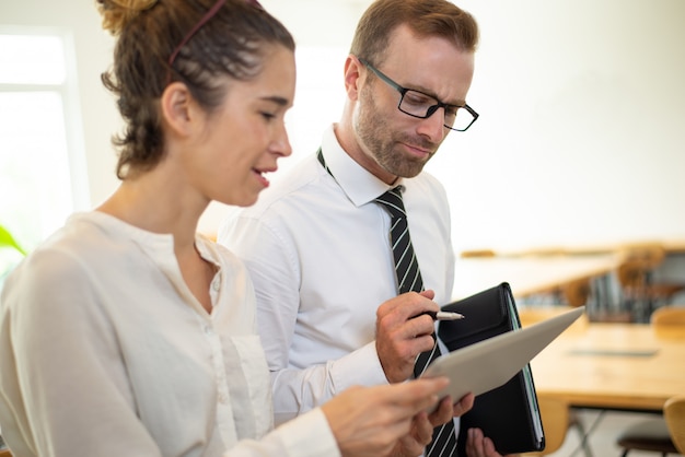 Free photo business woman showing something on tablet screen to thoughtful male colleague.