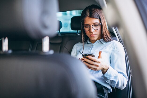 Business woman sitting in car and using phone