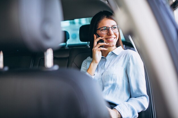 Business woman sitting in car and using phone