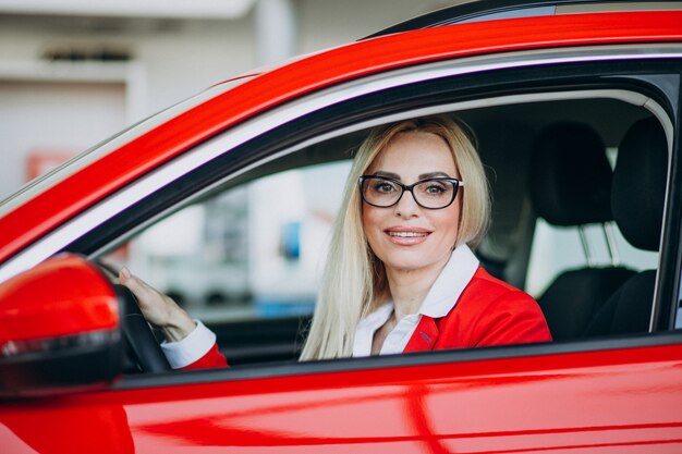 Бизнес женщина сидит в новой машине в автосалоне
