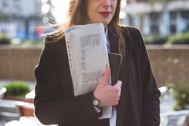 Business woman standing with newspaper outside