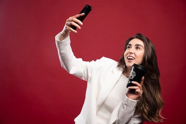 Business woman taking a selfie with a coffee cup 