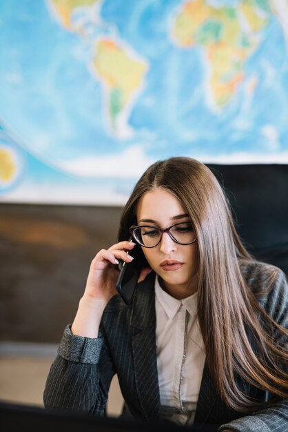 Business woman talking by phone sitting in office 