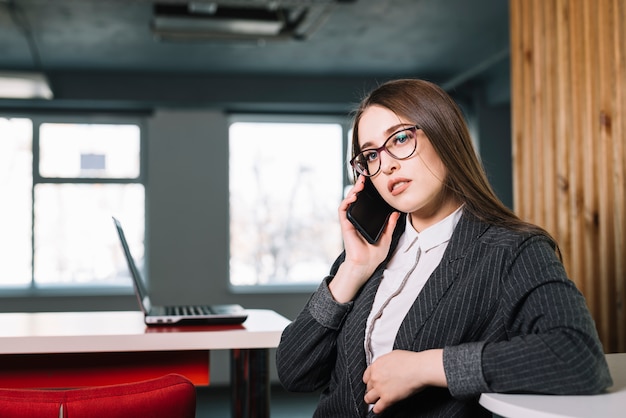 Business woman talking by phone at table