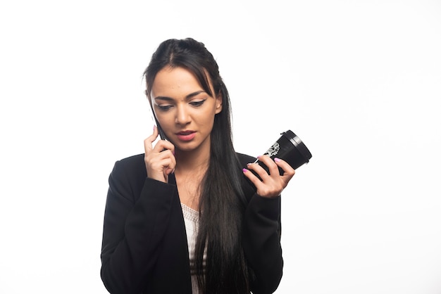 Business woman talking on cellphone on white wall