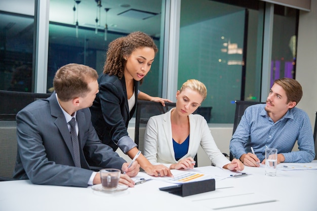 Business woman teaching a document to some colleagues