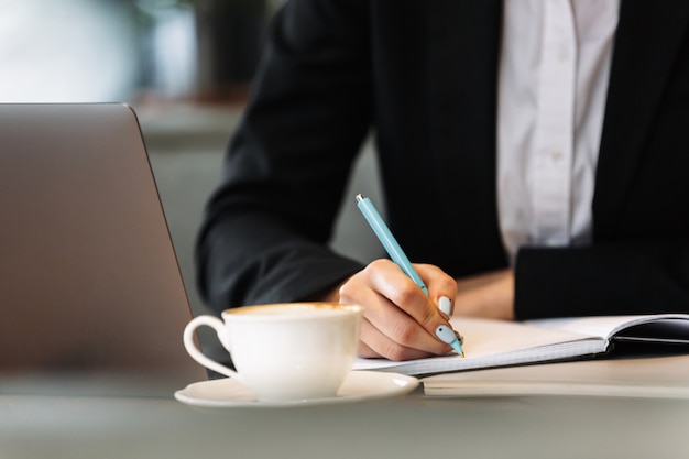 Business woman using laptop computer writing notes