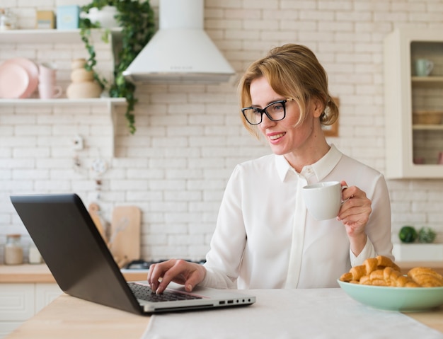 Business woman using laptop in kitchen 