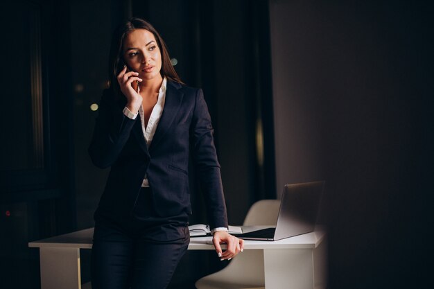 Business woman using phone in office and staying late by night