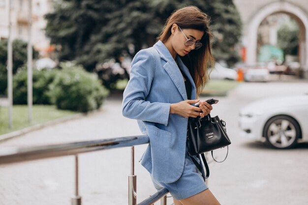 Business woman using phone outside the street