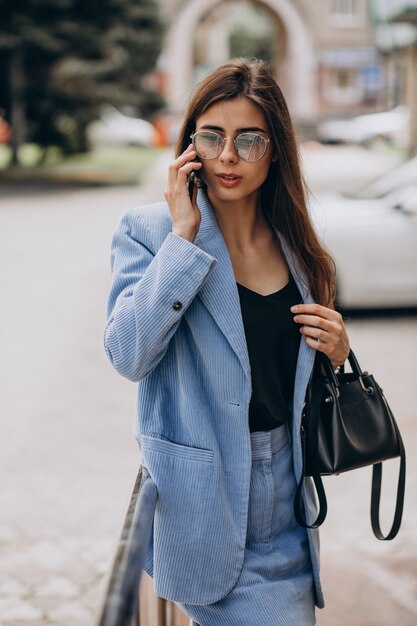 Business woman using phone outside the street