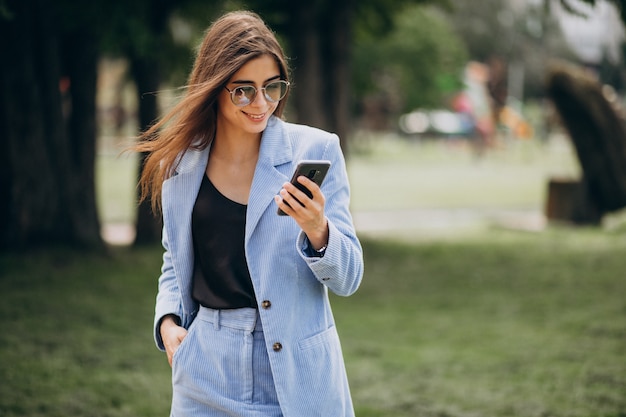 Business woman using phone in park