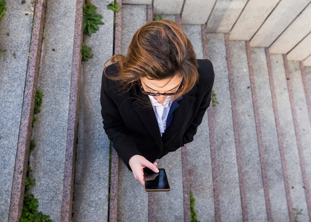 ビジネスの女性が階段の上にスマートフォンを使用して