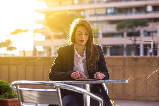 ビジネスの女性の外のテーブルでタブレットを使用して