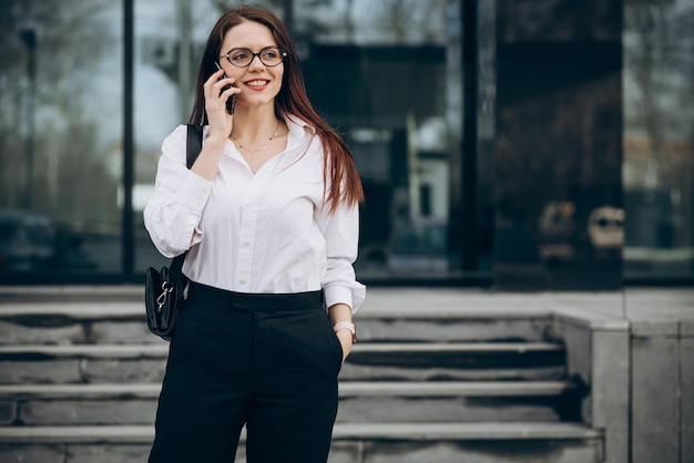 Business woman walking down the stairs and using phone