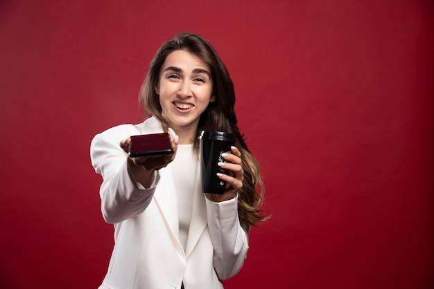 Деловая женщина с чашкой кофе предлагает телефон