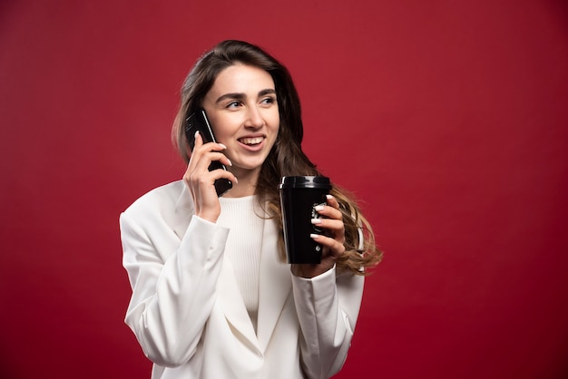 Business woman with a coffee cup speaking on phone 