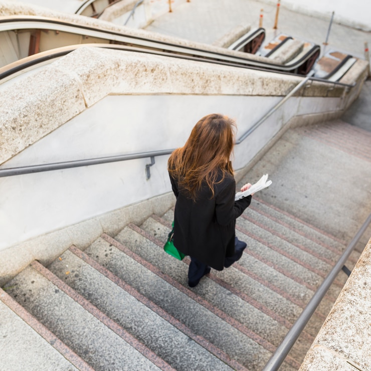 Free Photo business woman with newspaper walking down stairs 