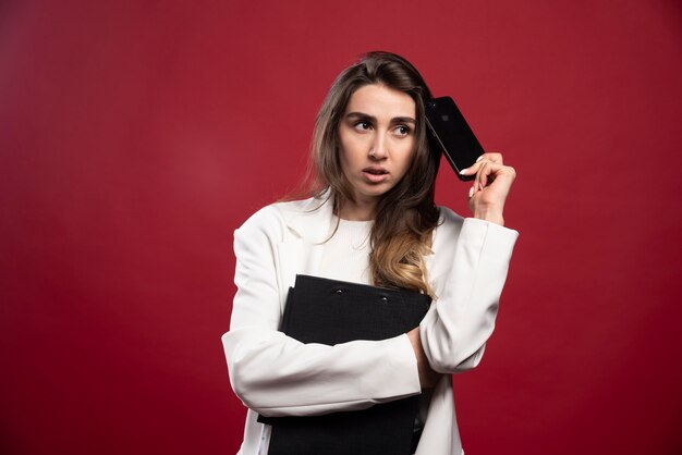 Business woman with phone holding notebooks 