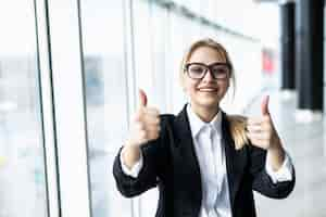 Free photo business woman with thumbs up in office with panoramic windows