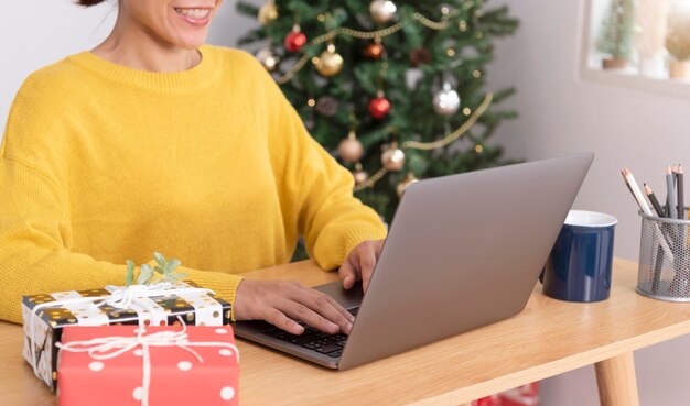 Business woman working on computer in Christmas day with gift box and christmas tree background.