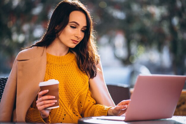 ビジネスの女性がコンピューターに取り組んでいるとコーヒーを飲む