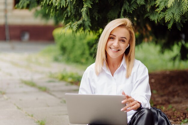 Бизнес женщина работает на ноутбуке снаружи в городском парке