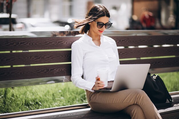 Business woman working on laptop outside the park