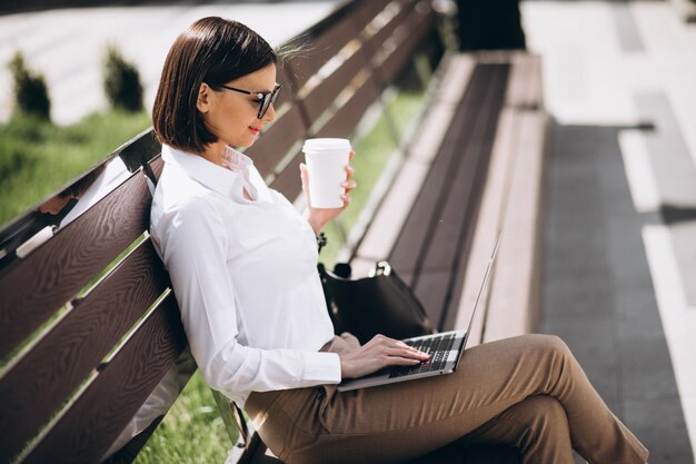 Business woman working on laptop outside the park