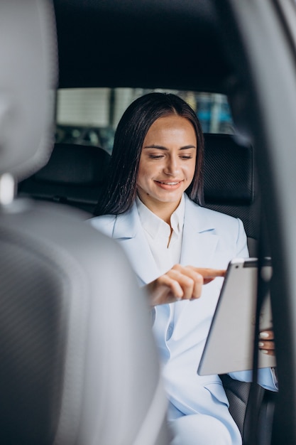 Donna d'affari che lavora su tablet nel sedile posteriore della sua auto