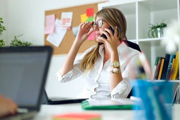 Business woman working with mobile phone in her office.