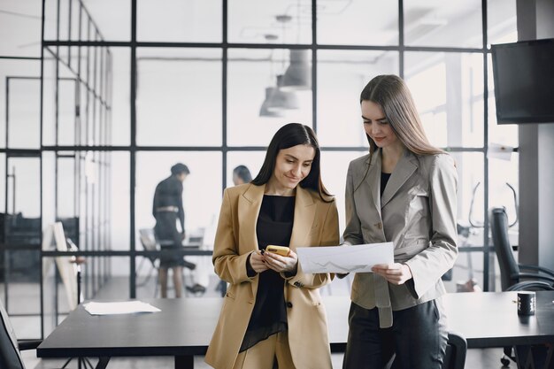 Business women talking near the desk during a coffee break in the hallway of the big corporation